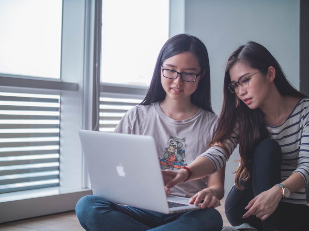 two girls are sitting near the computer